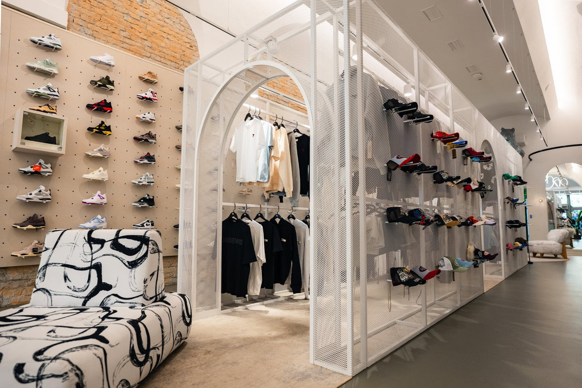 A white lattice fitting room with streetwear pieces and caps