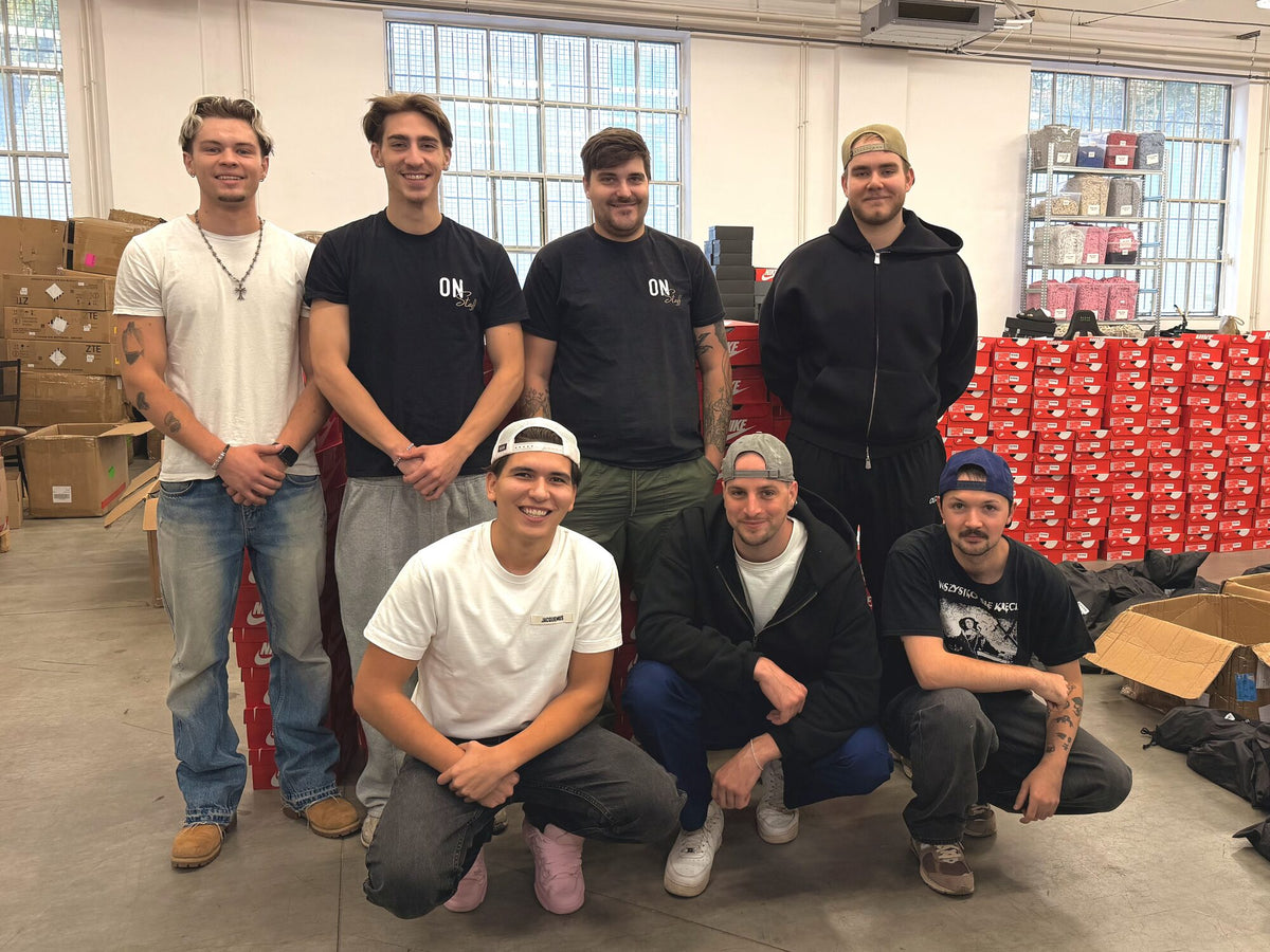 Group photo of the warehouse team in the new hall, with red Nike boxes behind them